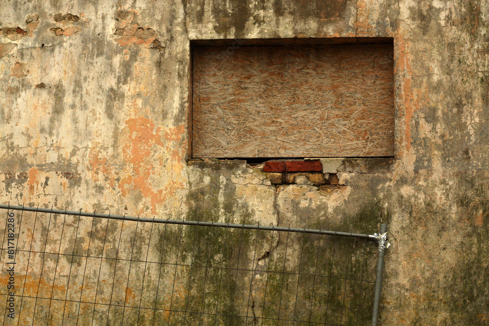Naklejka premium Grungy metal fence against dirty weathered cement wall.