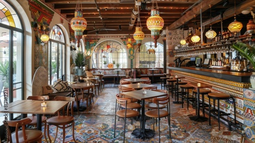 A cozy Spanish restaurant with a vibrant mosaic floor, colorful hanging lights, and wooden furniture. Bright sunlight streams through large arched windows, enhancing the warm, inviting atmosphere.