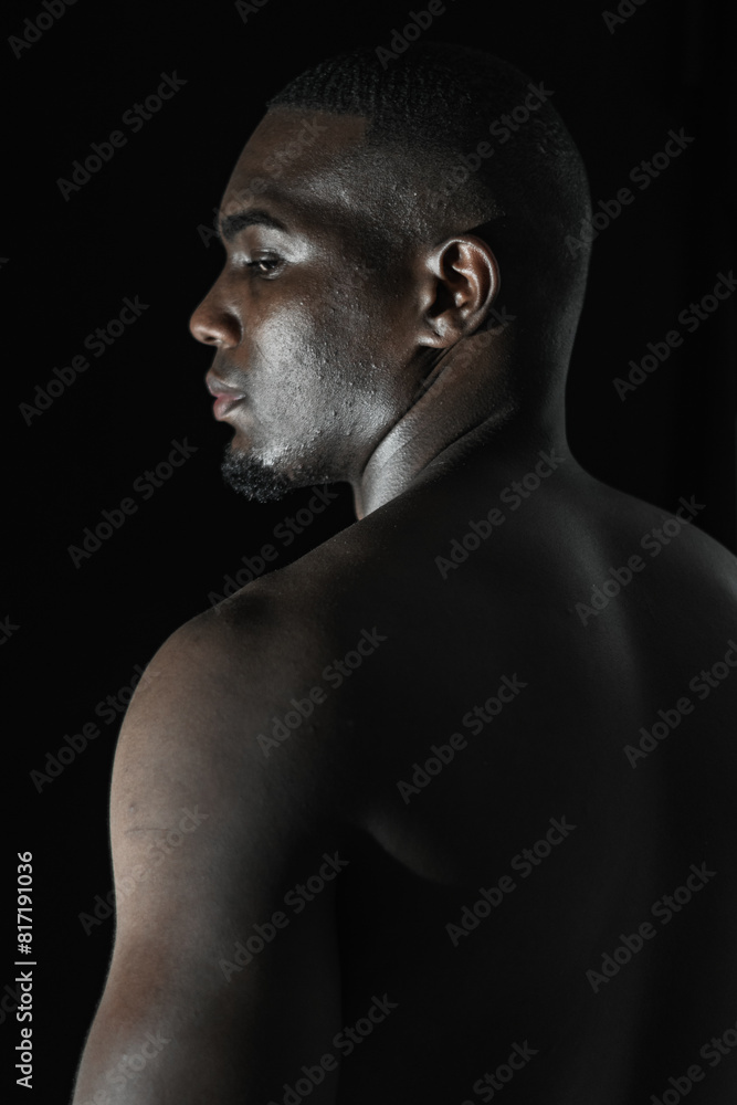 close-up of the back of a black African-American man looking out of the corner of his eye, on a black background with 90-degree lighting. close-up of the back of a black African-American man looking out of the corner of his eye, on a black background with 90-degree lighting.