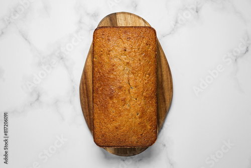 Banana bread loaf on a wooden board on marble background