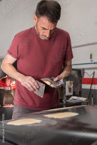 Auto Mechanic Preparing Body Filler for Car Hood Repair © Alejandro