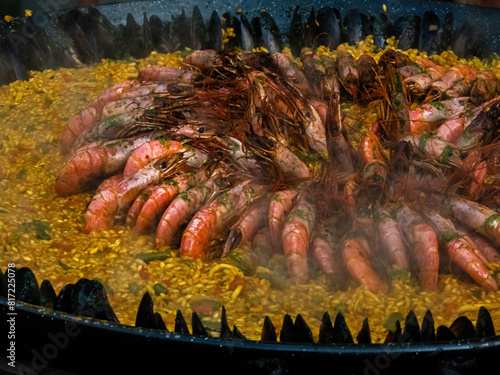 paella with rice, shrimp and shellfish in a large cauldron, street food (ID: 817225078)