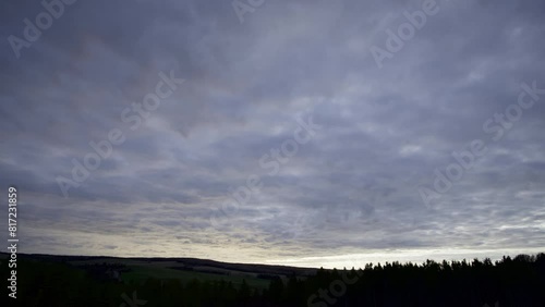 Flying puffy cloudy sunset time lapse in valley forest silhouette