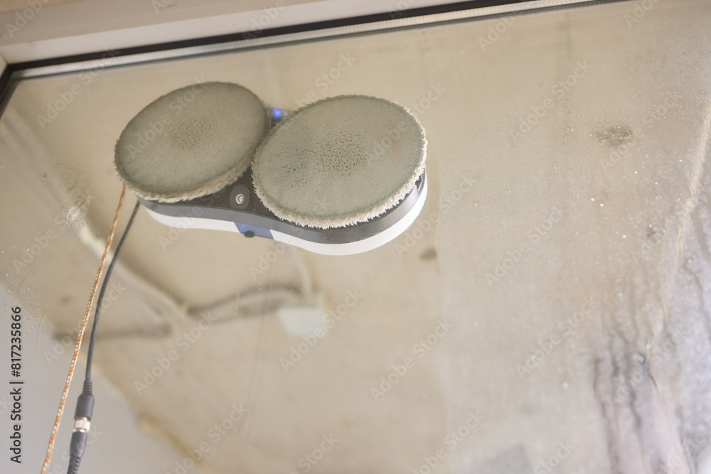A robotic white Automotive tire is cleaning a glass window A robotic white Automotive tire is cleaning a glass window