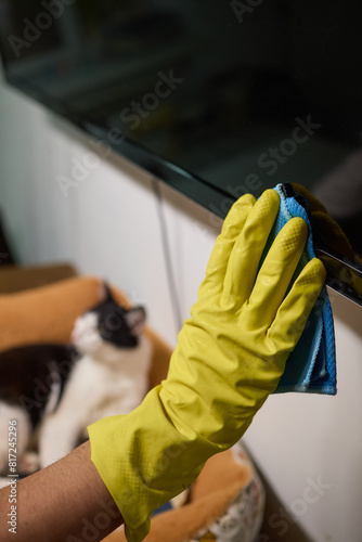 Close-up of hand cleaning television screen with cloth at home