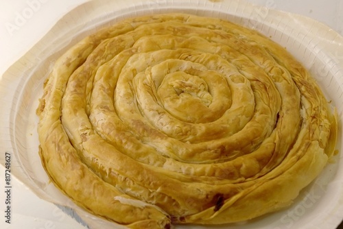 A photo of a cooked tasty twisted cheese pie in the shape of a roll  