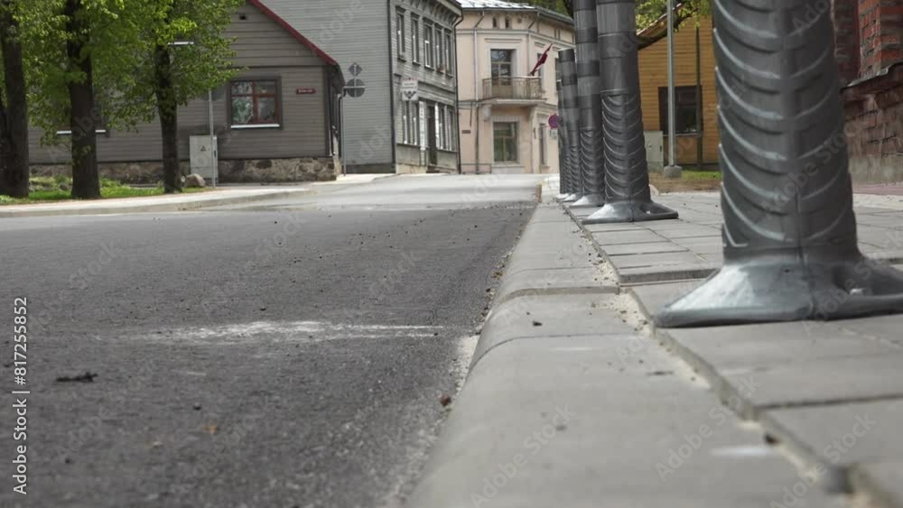 Low-angle view of a street with people walking in the background, focusing on the pavement and curb. Low-angle view of a street with people walking in the background, focusing on the pavement and curb.