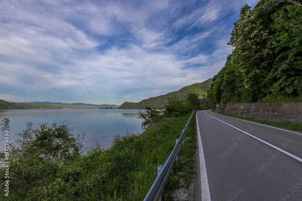 Obraz premium The tranquil scene is framed by a mountain range under a blue sky dotted with white clouds.