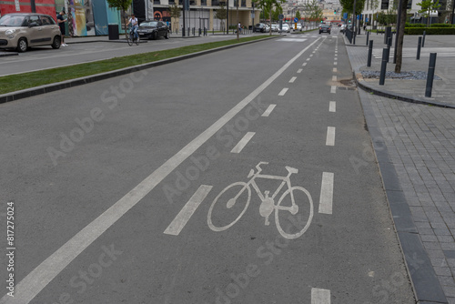 A well-marked bike lane on an urban road with clear road markings, a bicycle symbol, and white lines indicating the direction of traffic. The scene is devoid of people