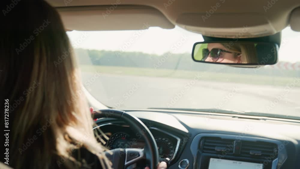 Woman driving car on country road at sunset. Back view of female driver wearing sunglasses in vehicle Woman driving car on country road at sunset. Back view of female driver wearing sunglasses in vehicle