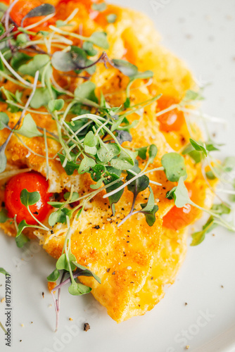 yellow egg omelette with cherry tomatoes, micro greens on white plate