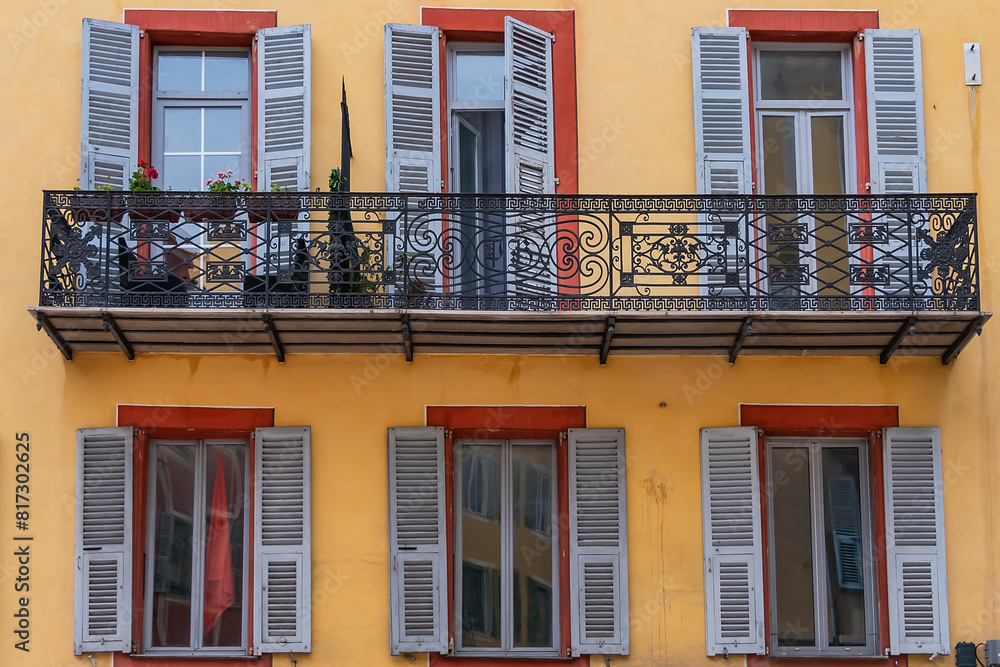 Fototapeta premium Architectural fragments of the facades of ancient houses in Nice: beautiful windows, balconies, shutters. Nice, capital of the Alpes-Maritimes department on the French Riviera.