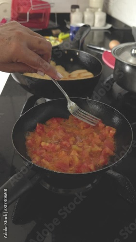 Preparation of Huevos Pericos with the traditional Colombian hogao based on onion, tomato and peppers. Arepas and Scrambled Eggs with hogao. Woman preparing hogao in a frying pan on a gas stove burner photo