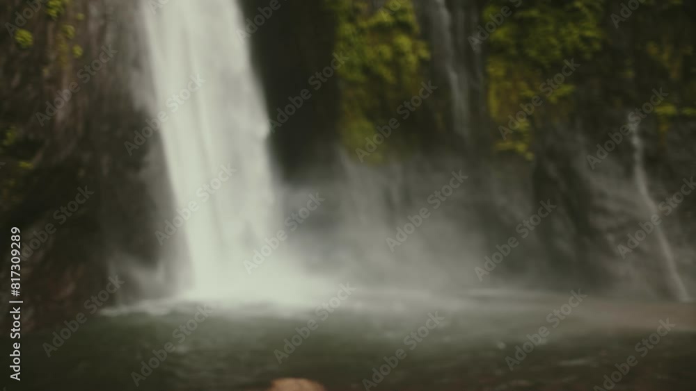 People slow motion jungle waterfall. Long hair woman enjoy tropic island landscape of powerful high waterfall in exotic rainforest. Bali Indonesia. Female on summer vacation. Close up back view People slow motion jungle waterfall. Long hair woman enjoy tropic island landscape of powerful high waterfall in exotic rainforest. Bali Indonesia. Female on summer vacation. Close up back view