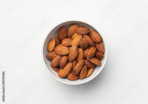 Almond nuts in the white bowl, on the white background top view
