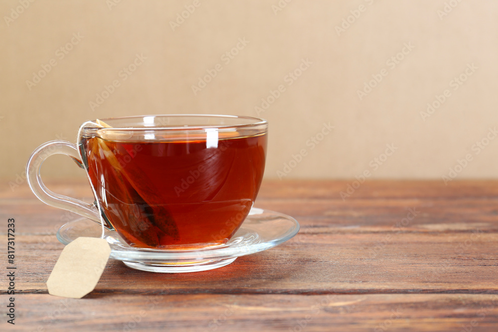 Brewing aromatic tea. Cup with teabag on wooden table. Space for text