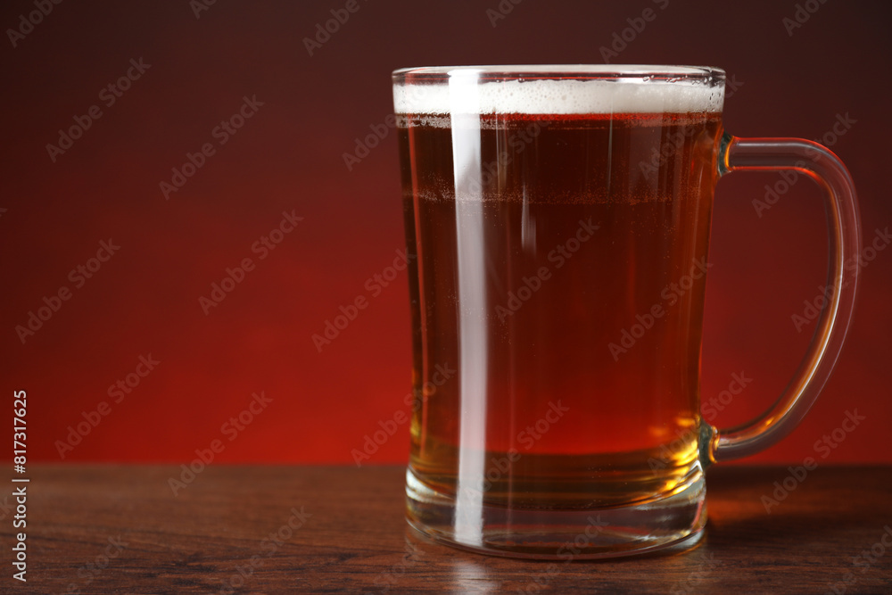 Mug with fresh beer on wooden table against color background, closeup. Space for text Mug with fresh beer on wooden table against color background, closeup. Space for text