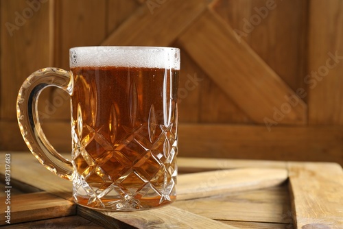 Mug with fresh beer on wooden crate, closeup. Space for text photo