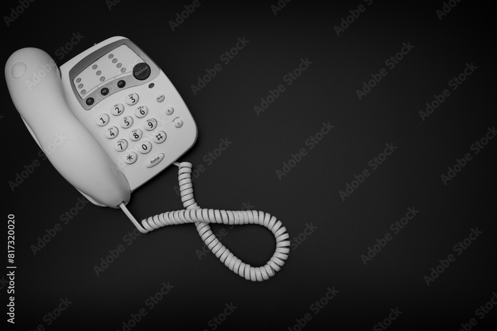 A black and white photo of a vintage style 1990's telephone on a black background, 90's technology photo