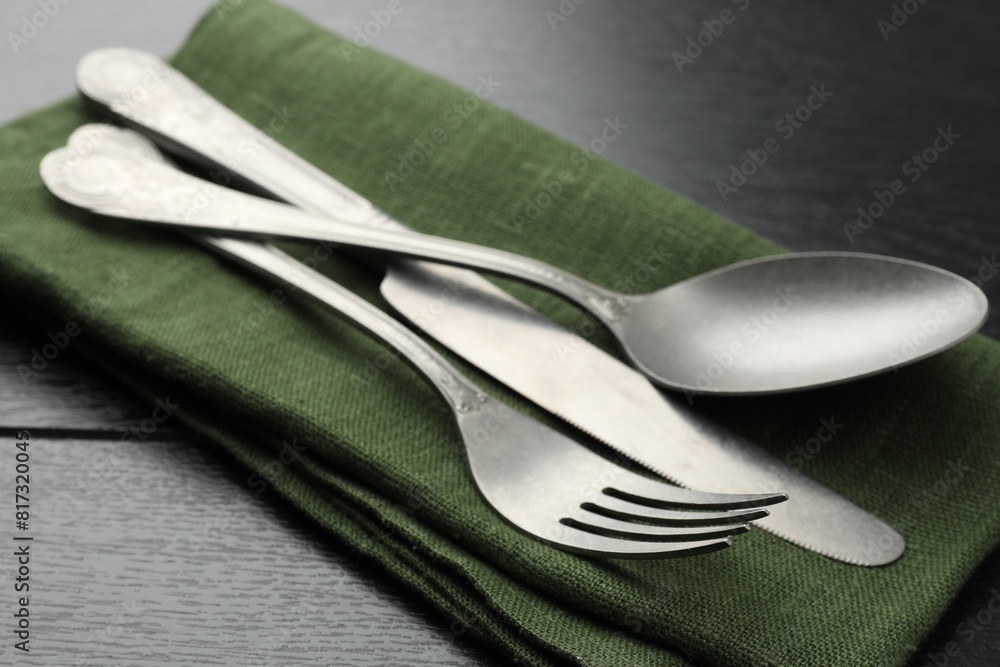 Stylish setting with cutlery and napkin on black wooden table, closeup Stylish setting with cutlery and napkin on black wooden table, closeup