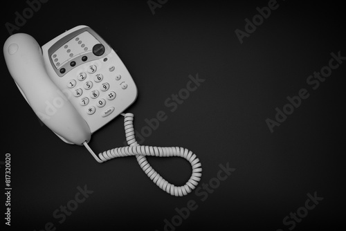 Obraz na płótnie A black and white photo of a vintage style 1990's telephone on a black background, 90's technology photo w salonie