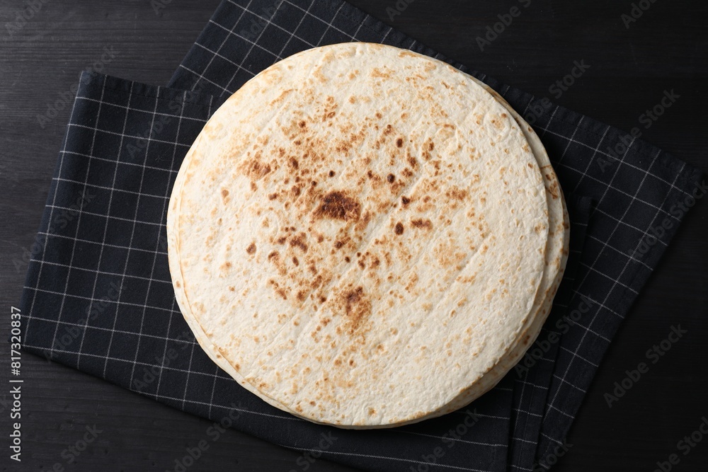 Many tasty homemade tortillas on black wooden table, top view Many tasty homemade tortillas on black wooden table, top view