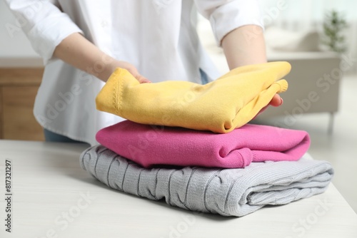 Woman folding clothes at white wooden table indoors  closeup