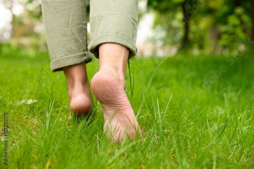 Woman walking barefoot on green grass outdoors, closeup © New Africa