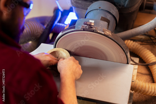 Tableau sur toile Artisan sanding wooden object on disc sander in assembling shop