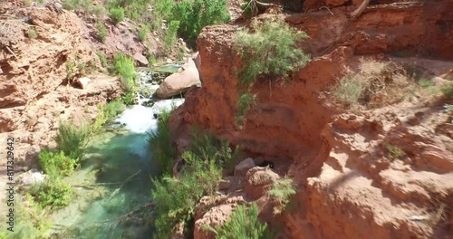 Flying backwards over hidden waterfall and pond in desert area photo