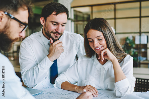 Group of young male and female colleagues discussing ideas for startup project creating new architect sketches together, successful caucasian men and woman enjoying cooperation in company office