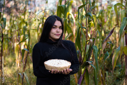 La cosecha del esfuerzo,una campesina bonita orgullosa muestra el fruto de su trabajo en la tierra, sosteniendo en su mano una canasta rebosante de maíz,alegre mujer,trabajo,estilo de vida photo