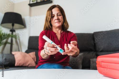 Mature Woman Testing Blood Sugar Levels at Home photo