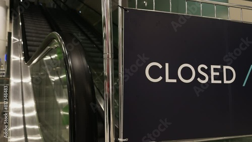 An escalator in a building is closed with a sign next to it