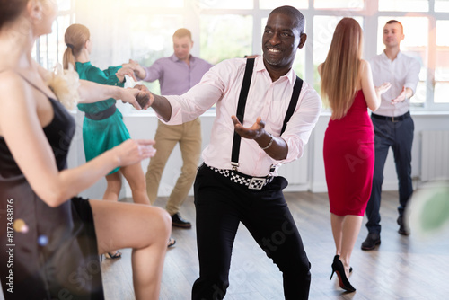 Positive woman and man dancing foxtrot in pair during group dance party photo