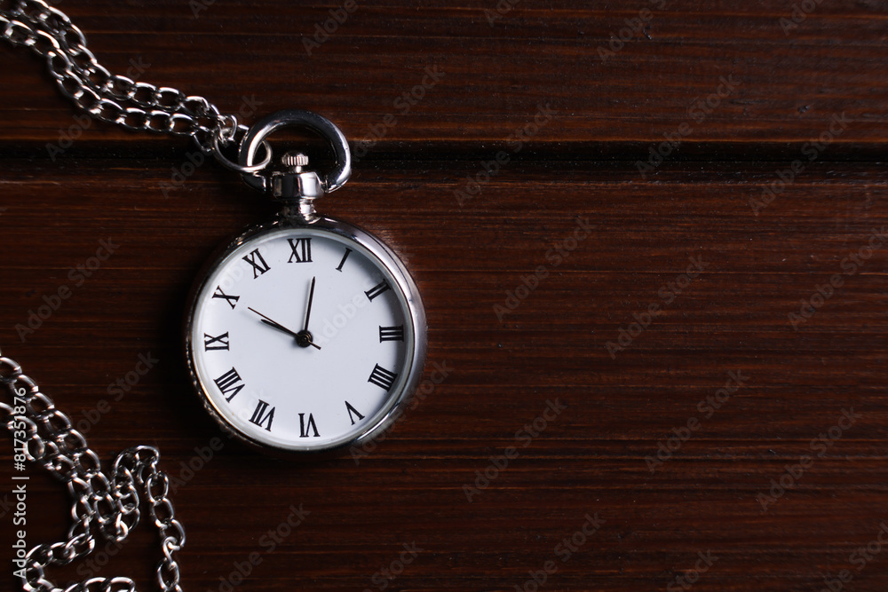 Silver pocket clock with chain on wooden table, top view. Space for text Silver pocket clock with chain on wooden table, top view. Space for text