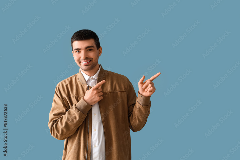 Young man pointing at something on blue background Young man pointing at something on blue background
