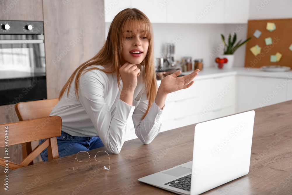 Teenage girl with laptop video chatting in kitchen Teenage girl with laptop video chatting in kitchen