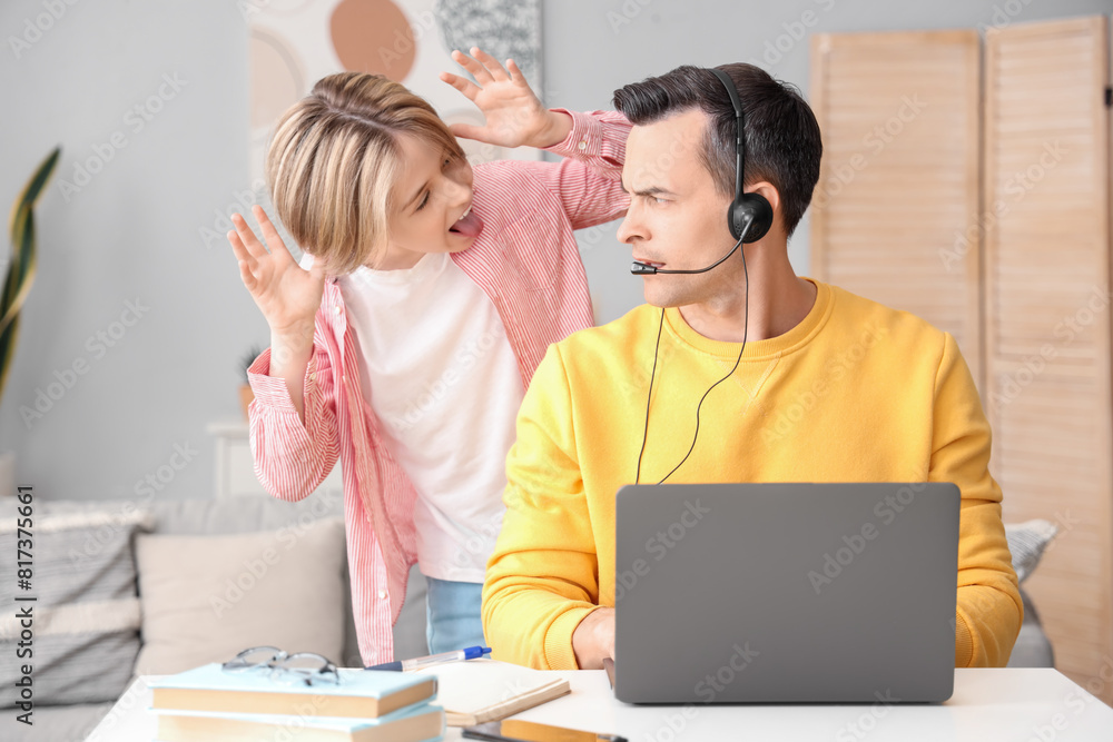 Working young man with his noisy little son at home Working young man with his noisy little son at home