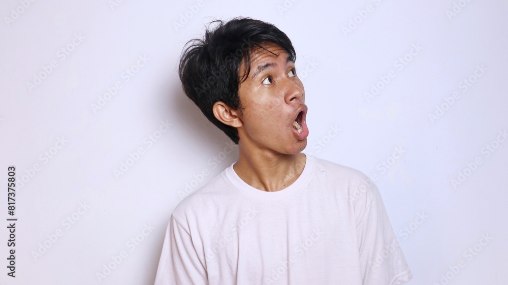 Obraz premium Young Asian man in white shirt with funny shocked gesture looking to the side