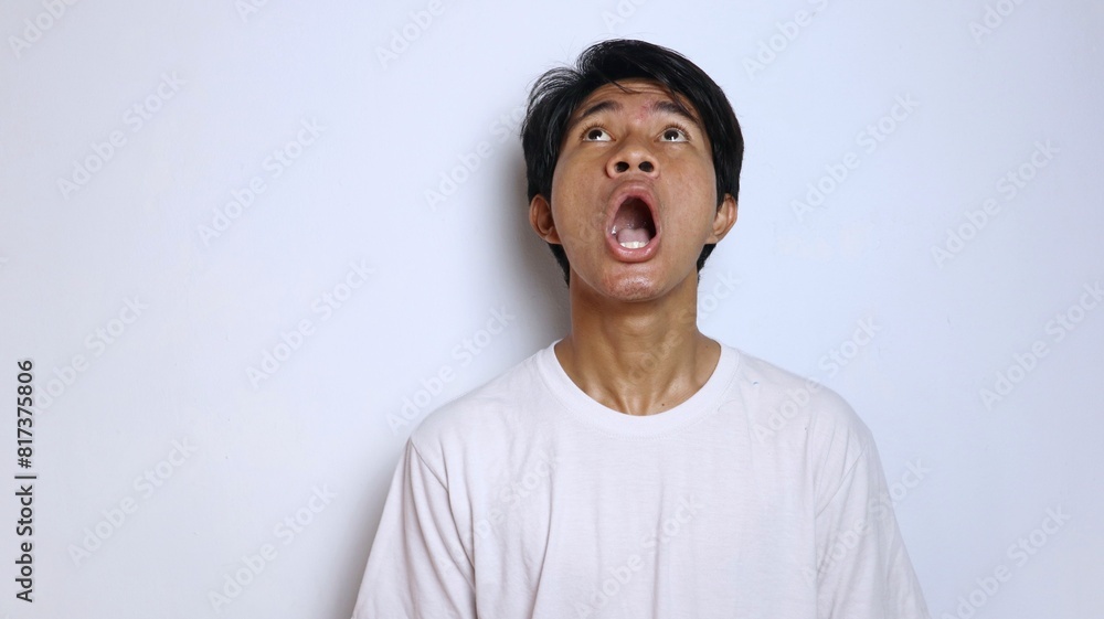 Young Asian man in white shirt with funny shocked gesture looking up Young Asian man in white shirt with funny shocked gesture looking up