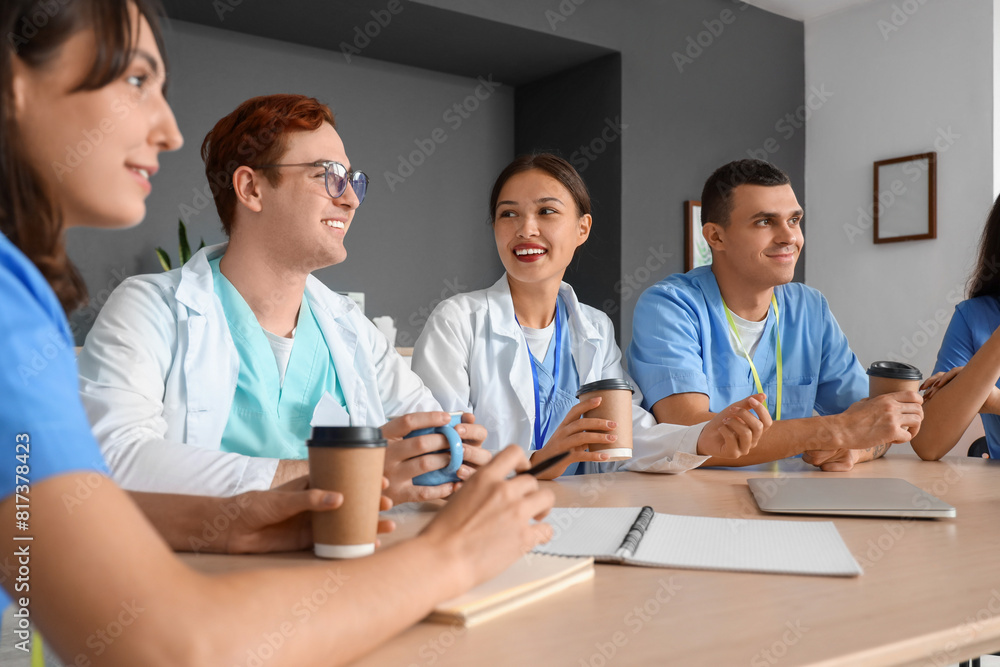 Team of young doctors having lunch at table in hospital kitchen