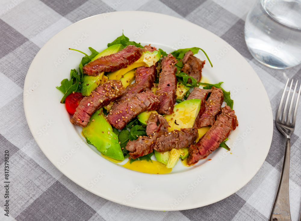 Delicious fried beef with avocado, parsley, sesame and tomatoes