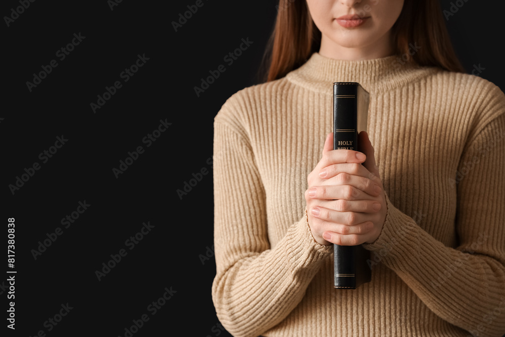 Young woman with Holy Bible praying on black background, closeup Young woman with Holy Bible praying on black background, closeup