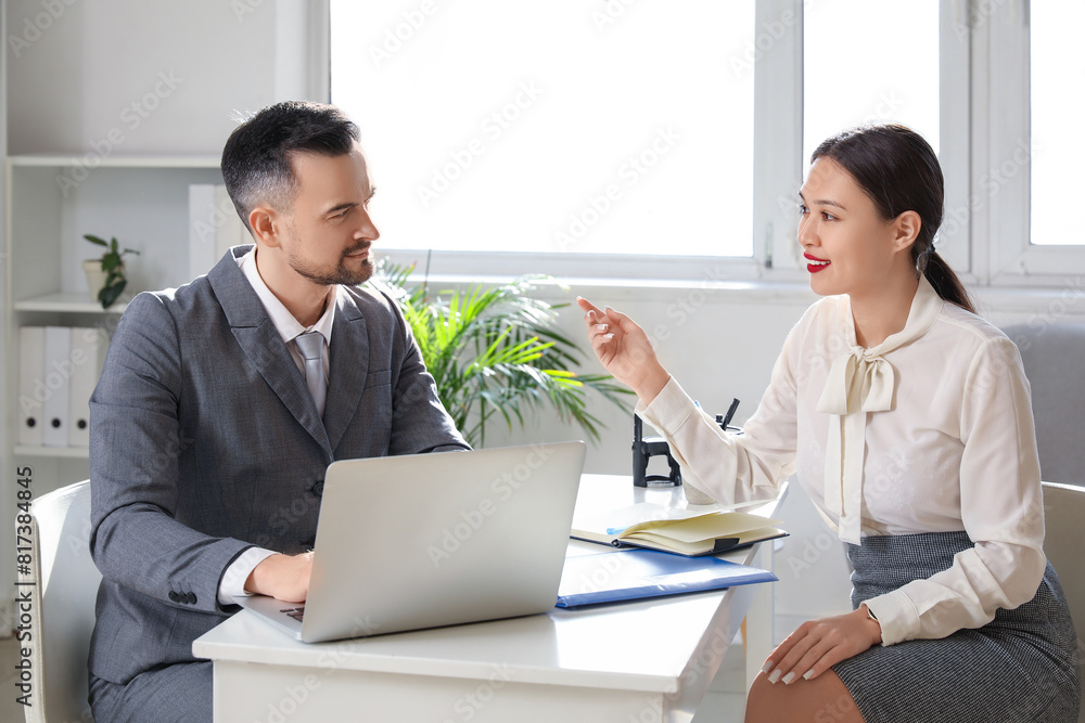 Human resources manager with laptop interviewing female applicant in office Human resources manager with laptop interviewing female applicant in office