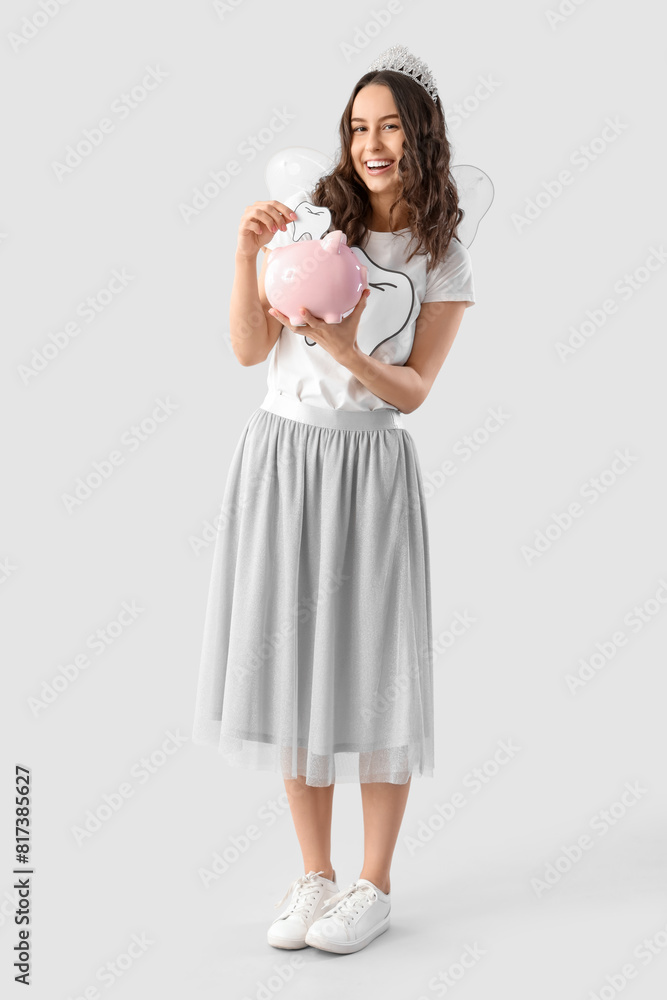 Tooth Fairy with piggy bank on light background Tooth Fairy with piggy bank on light background
