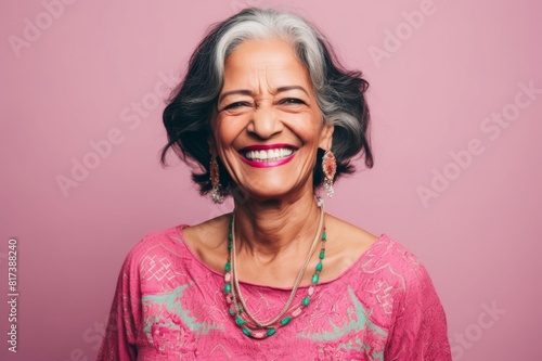 portrait of smiling senior woman wearing salwar kameez on pink background photo