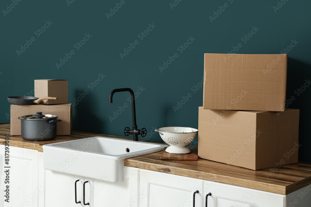 Kitchen counters with cardboard boxes and sink near green wall. Moving house concept Kitchen counters with cardboard boxes and sink near green wall. Moving house concept