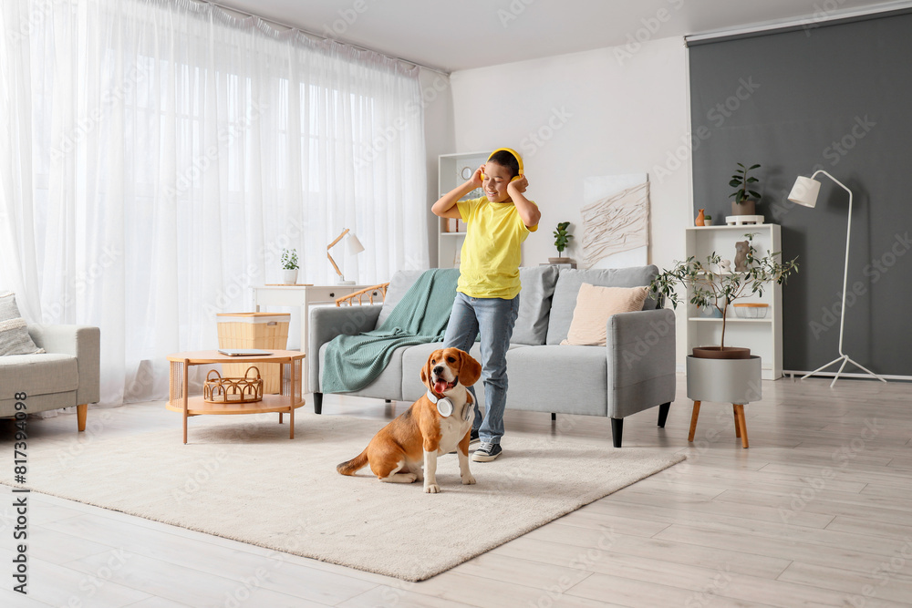 © Pixel-Shot - Little African-American boy and cute beagle dog with headphones listening to music at home
