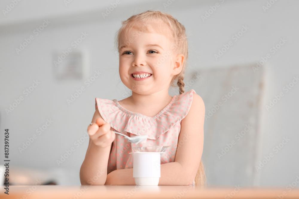 Happy little girl with spoon and yogurt at home Happy little girl with spoon and yogurt at home